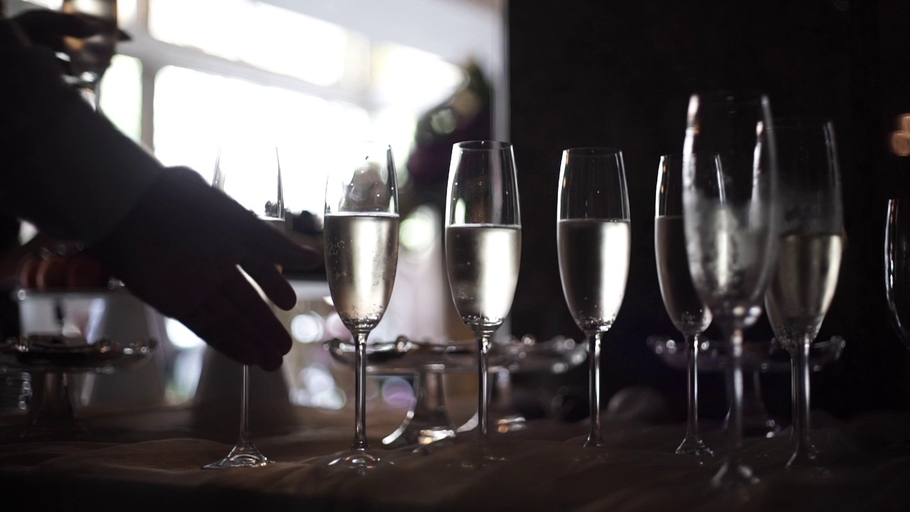 特写的男性和女性的手从桌子上拿一杯香槟。特写镜头的客人拿着香槟。人需要眼镜视频素材