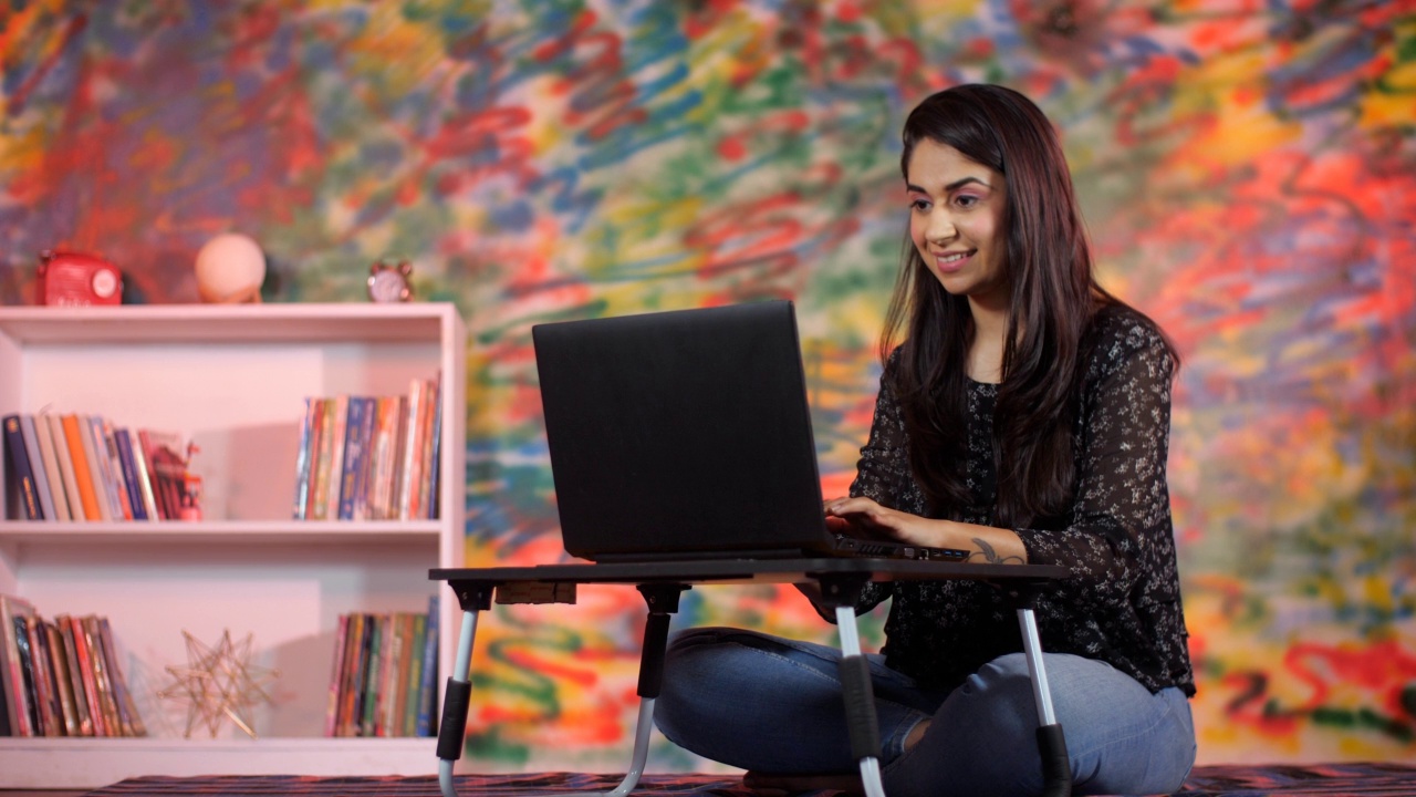 一位年轻的女商人在一家色彩斑斓的咖啡馆里用笔记本电脑工作——在任何地方工作，在家工作视频素材