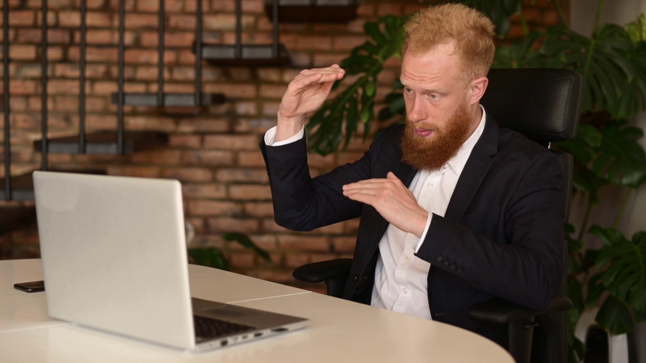 穿着正装的红发大胡子商人正在用笔记本电脑进行视频通话视频素材
