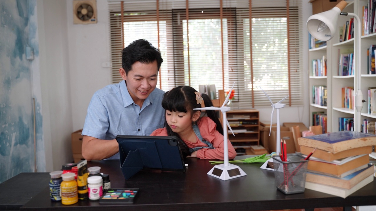 亚洲父亲教他的女儿学习与电子学习，同时在家工作视频素材