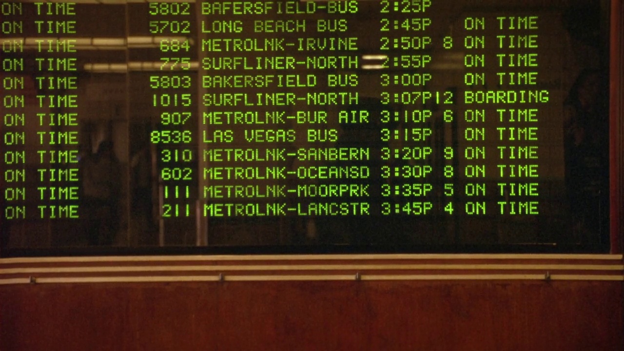 联合车站电子列车时刻表的中角度。见绿色文字的抵港及离港名单。地点是加利福尼亚和拉斯维加斯。看到板更新。人们走到黑板前查看时刻表视频下载