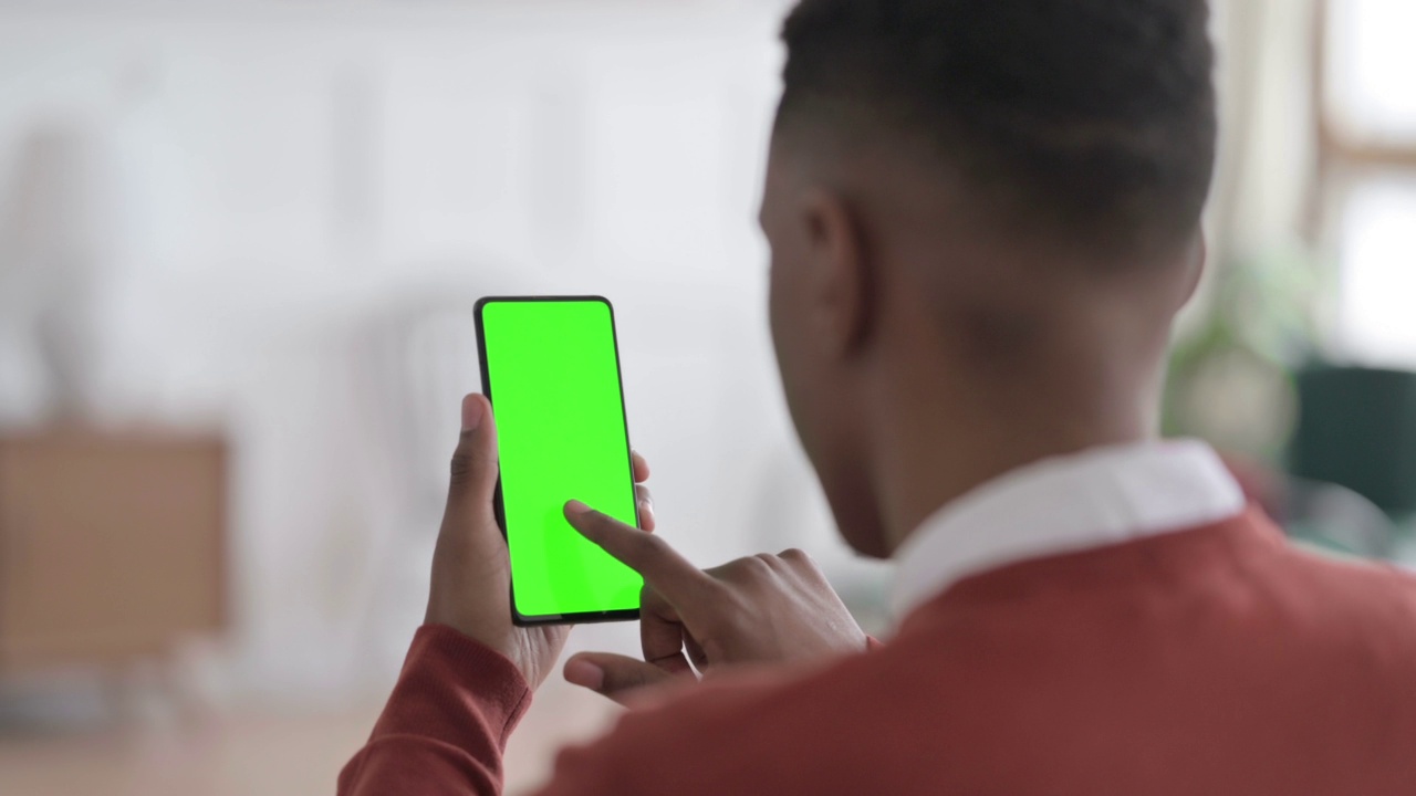 非洲人看绿色屏幕智能手机的后视图视频素材