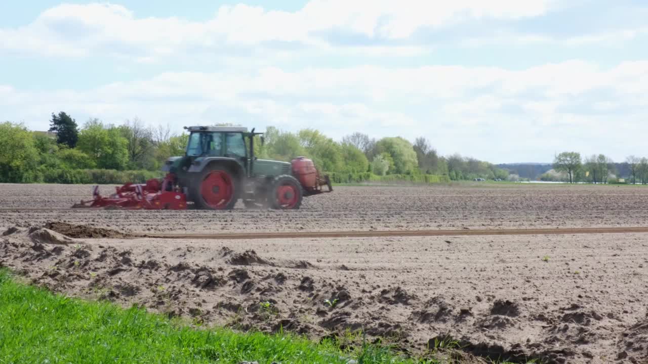 农民在春天用拖拉机犁地。红色农场机器和设备的侧面视图。视频下载