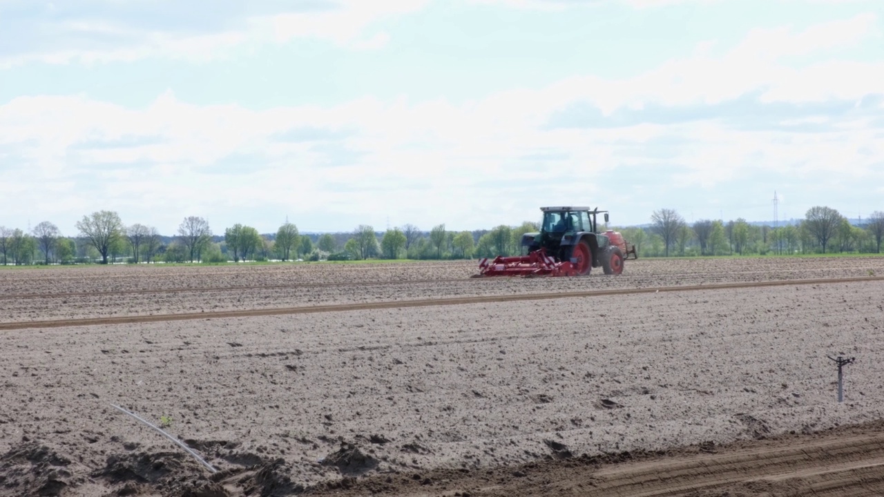 农民在春天用拖拉机犁地。红色农场机器和设备的侧面视图。视频下载