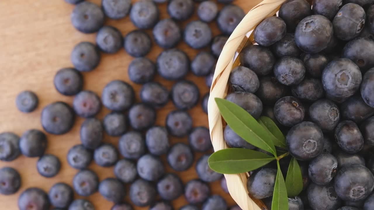 蓝莓和绿叶在一个旋转的篮子背景。新鲜和成熟的有机蓝莓Rote背景。视频下载