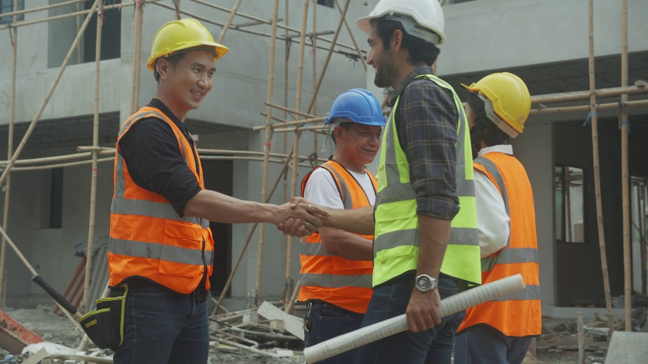 年轻的亚洲承包商团队和合作伙伴握手为团队合作成就，工程师和施工现场，建筑师握手为成功的协议和共同处理。视频素材