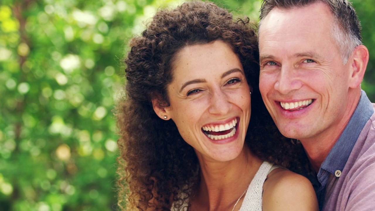 肖像开朗成熟夫妇笑与大微笑和粘在一起在花园或公园户外与copyspace。幸福的男女在爱的关系享受无忧无虑的日子视频下载