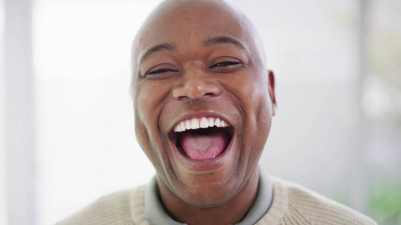 一张快乐微笑的非裔美国商人的脸。一名惊讶的黑人张开嘴笑着表示高兴。成熟的男性对滑稽的笑话做出反应，露出他天然的白色牙齿视频下载