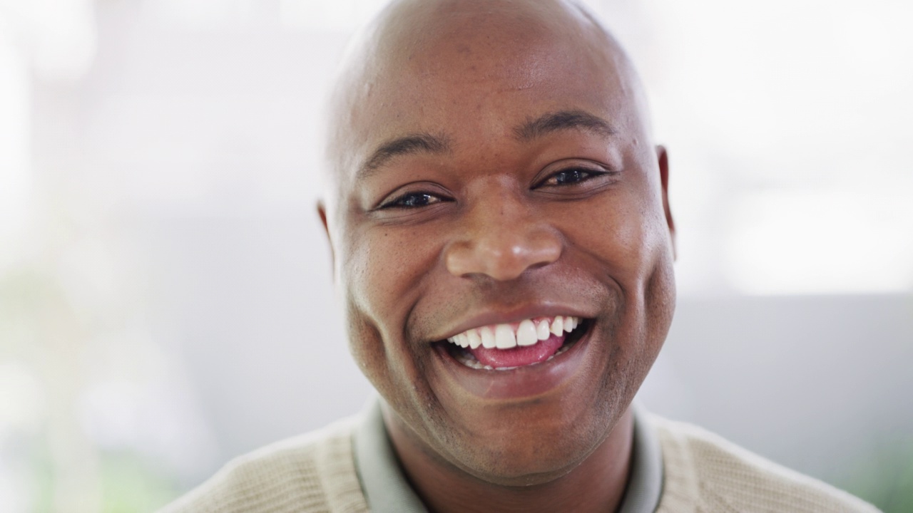 一个成熟的非洲裔美国人的脸微笑和大笑的肖像，露出洁白无瑕的牙齿。一个快乐的，英俊的黑人男子的头像，他在笑一个有趣的笑话时露出牙齿视频下载