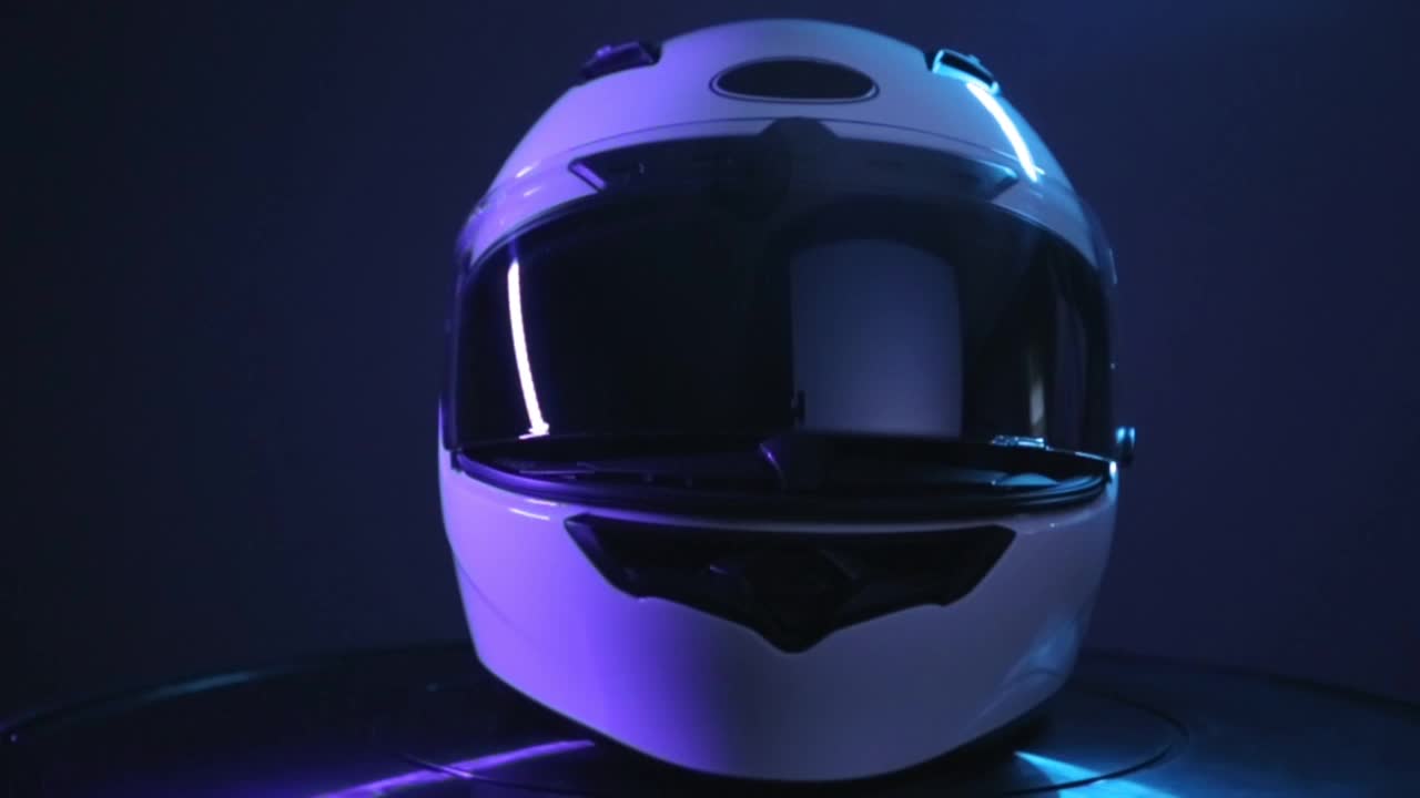 白色摩托车全脸头盔旋转在黑色背景。视频下载