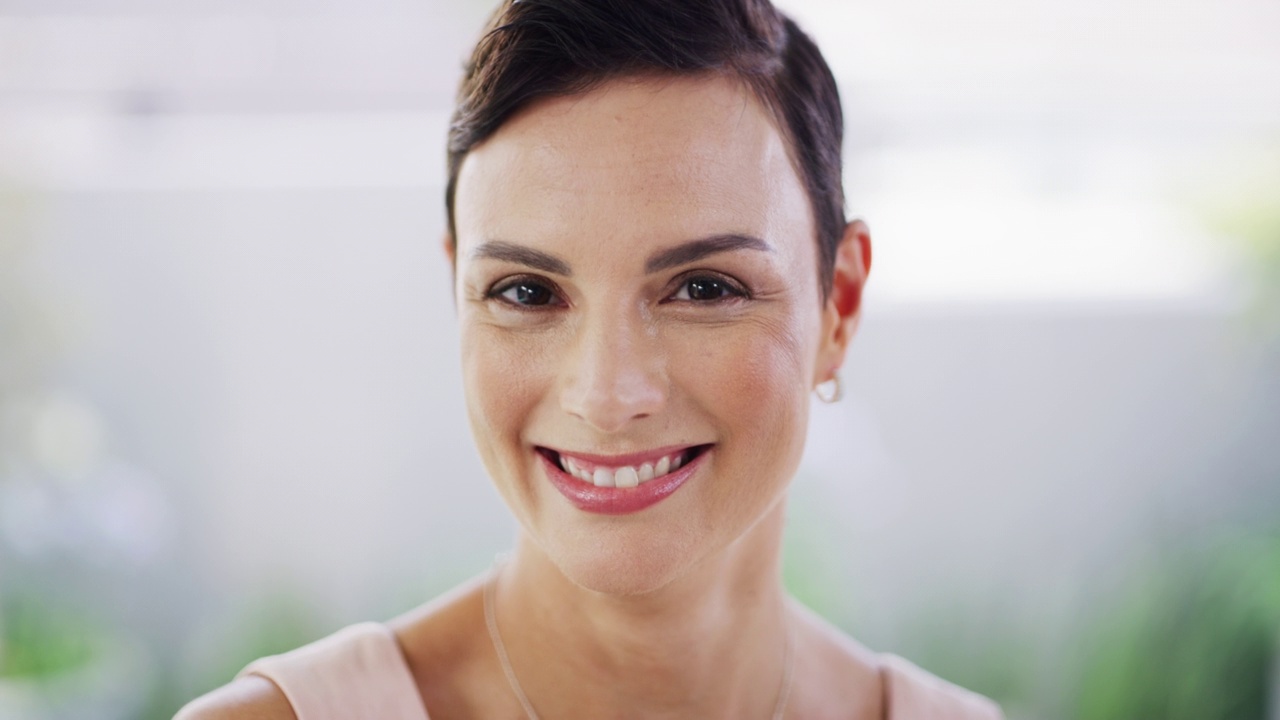 一位前卫成熟的女商人站在现代办公室微笑的肖像。一个雄心勃勃的企业家和坚定的领导者的脸，带着一个大大的微笑，准备在创业公司取得成功视频下载