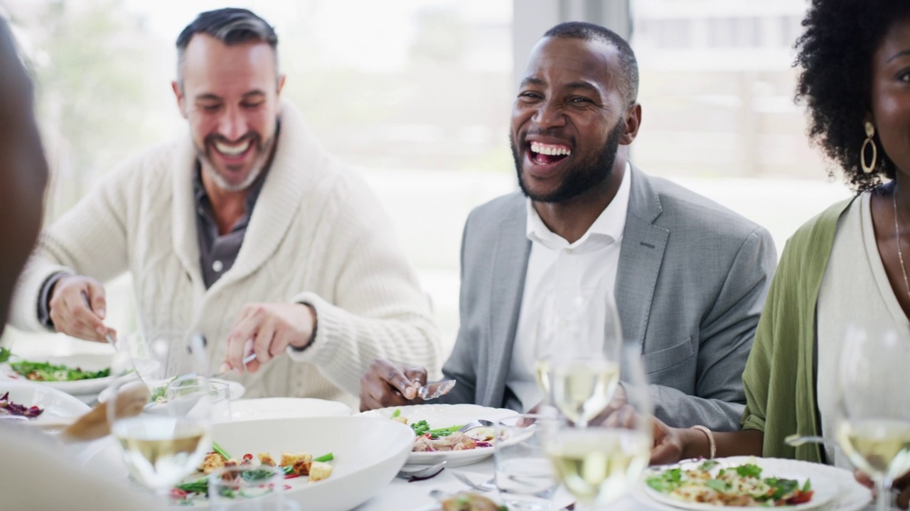 各种各样的人在一起吃饭开玩笑和大笑。微笑的朋友坐在一起享受美味的午餐或晚餐。男人和女人享受食物，感到快乐和社交视频下载
