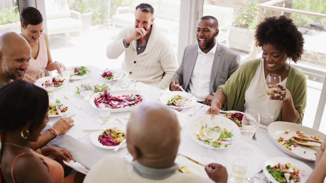 一群形形色色的好朋友在上面吃喝。人们在餐馆或家里围坐在桌子旁举行午餐聚会。快乐的男人和女人在吃饭的时候互相交流视频下载