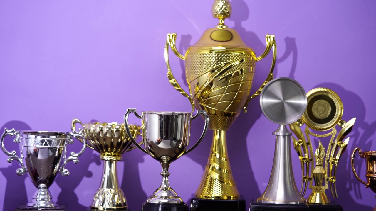 一组奖杯在紫色背景下排成一行视频素材