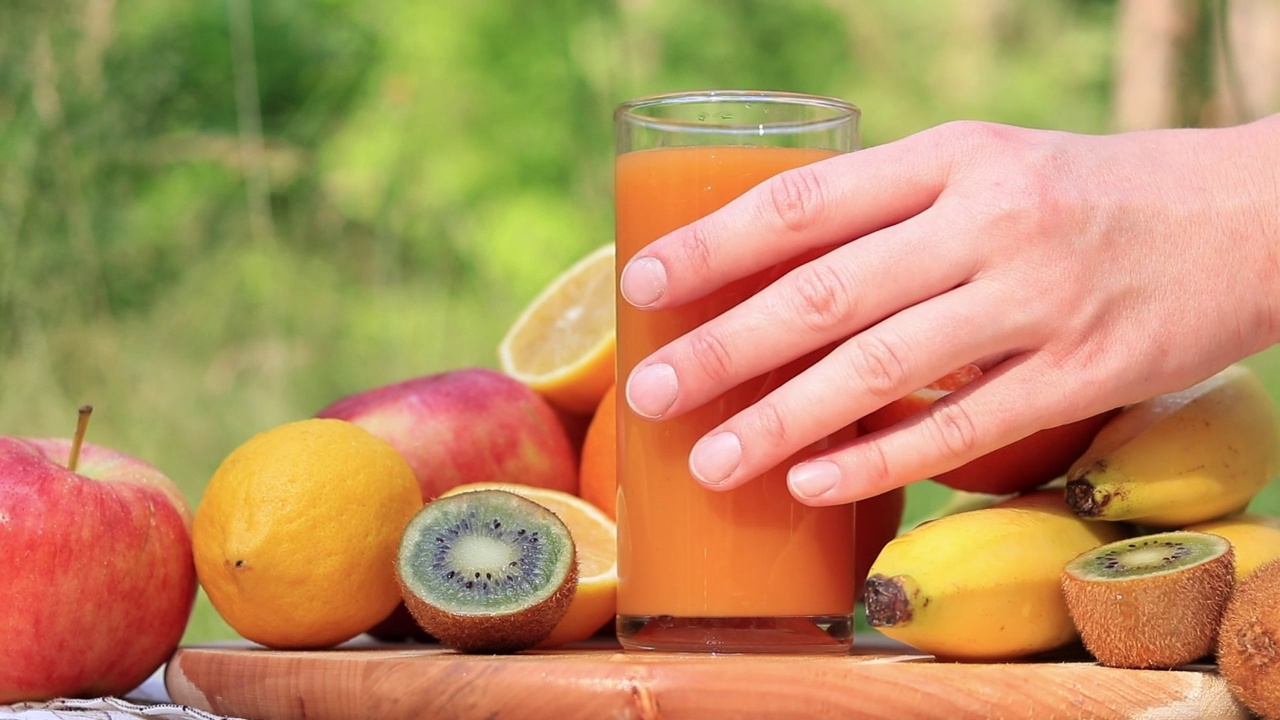 一个女人的手喝了一杯复合维他命汁。视频广告果汁，维生素和健康的生活方式视频下载