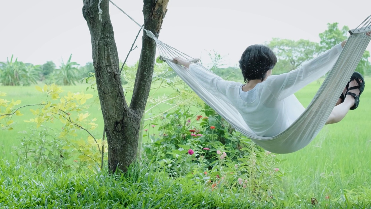 外出呼吸新鲜空气，坐在挂在树上的吊床上，感觉很自由视频下载