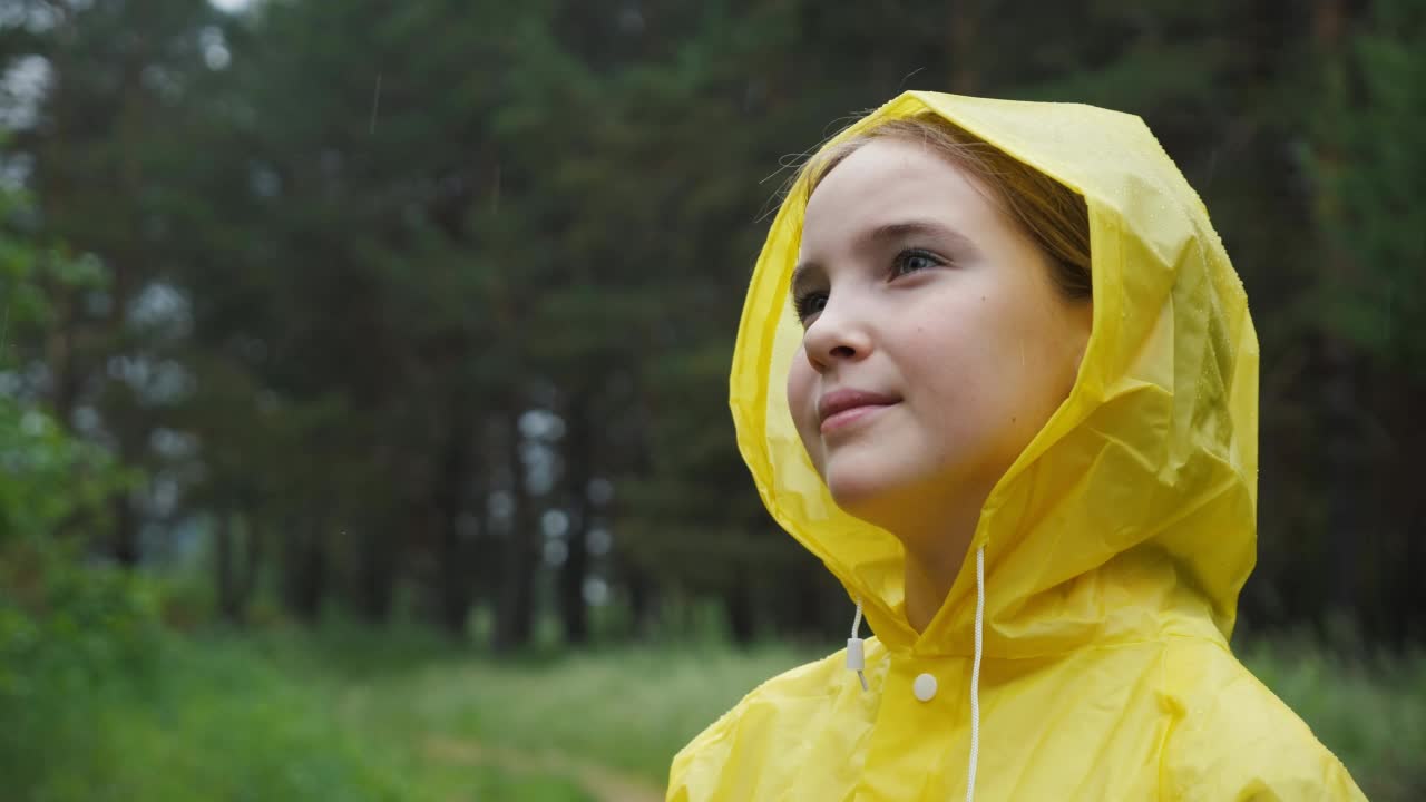 沉思的女孩望向别处，享受森林里的雨天视频素材