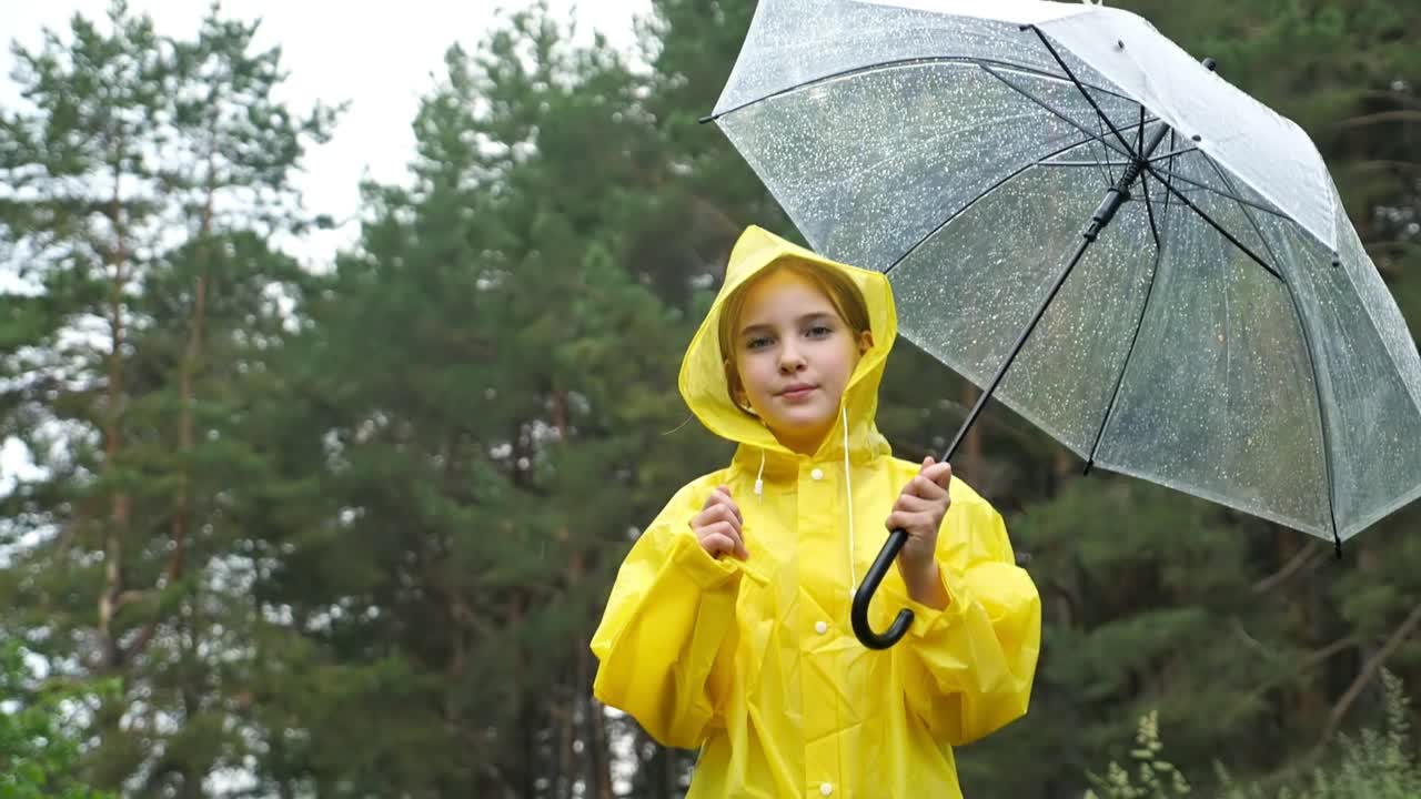 穿着黄色雨衣的女孩张开双手高高跳起视频素材