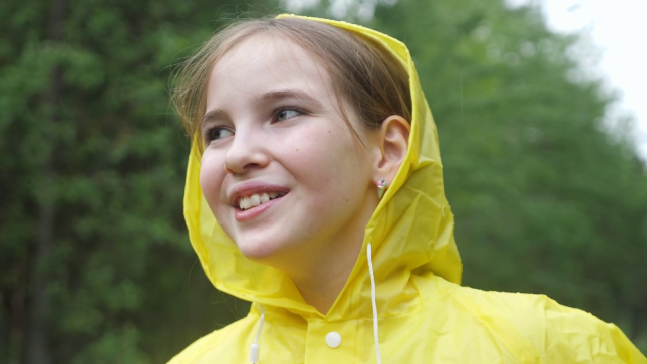 穿着黄色雨衣的快乐女孩笑着环顾四周视频素材