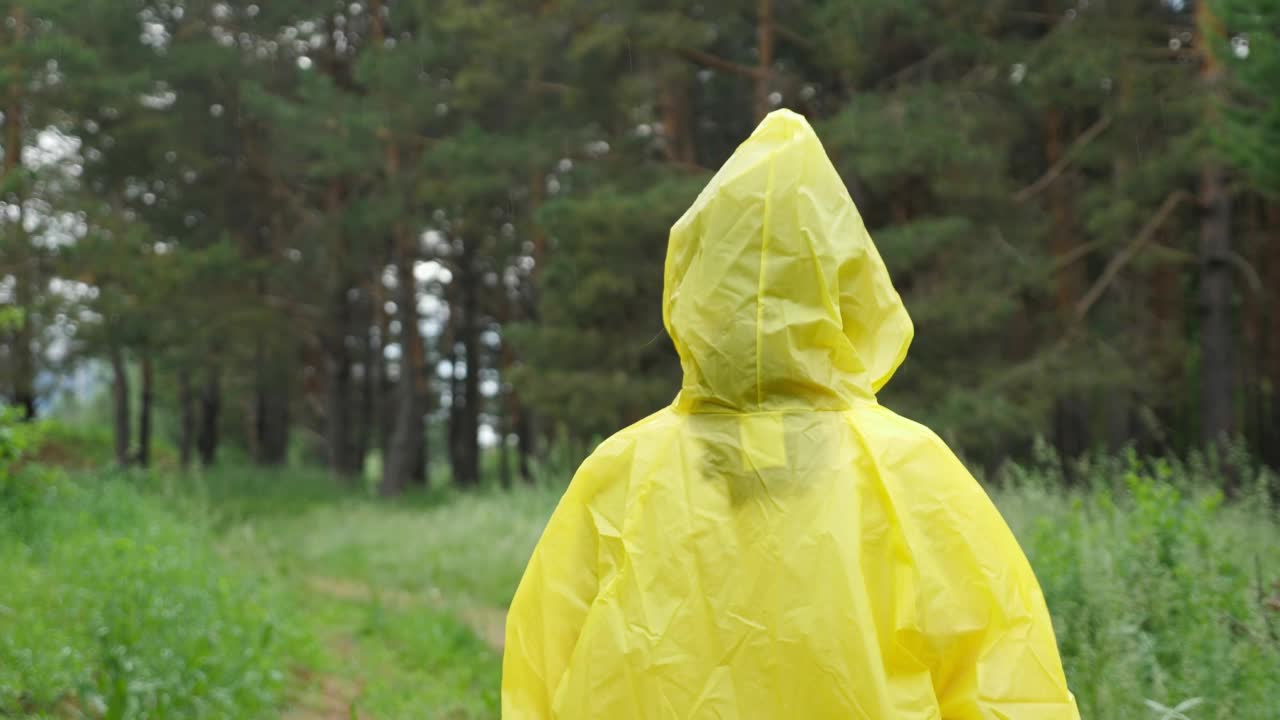 穿着黄色雨衣的快乐女孩走在森林的地面上视频素材