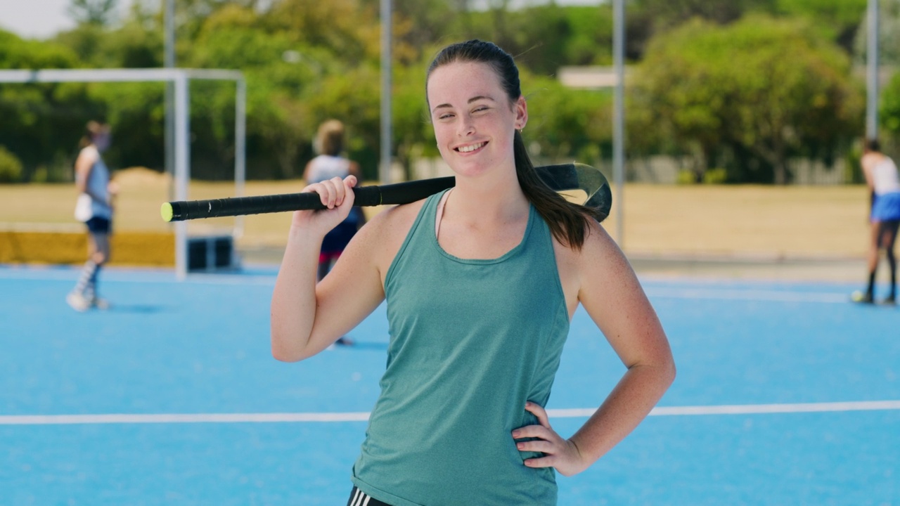 曲棍球运动员的肖像，拿着一根棍子和微笑在体育场上。自信的白人青少年运动员，准备好和她的高中或大学队的比赛或训练视频下载