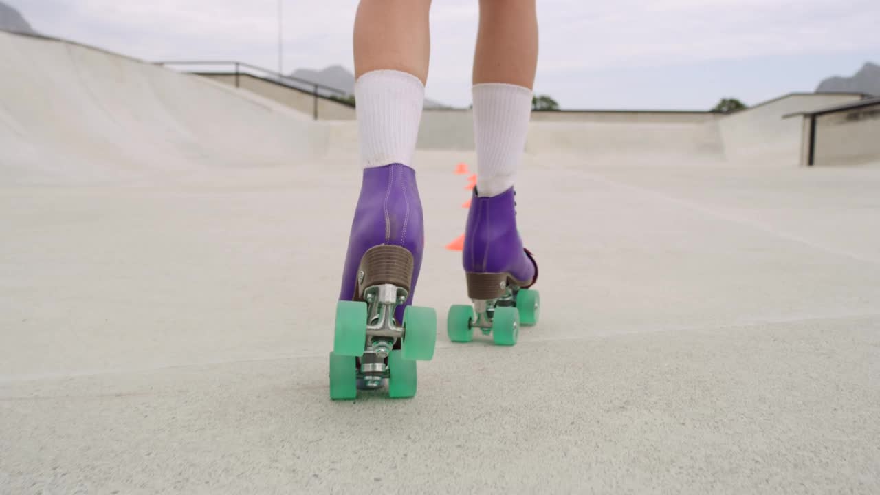 特写的女性腿轮滑在一个滑冰公园外面。熟练的滑冰女孩或人骑快速通过锥。穿着老式的彩色轮滑鞋练习体育比赛视频素材