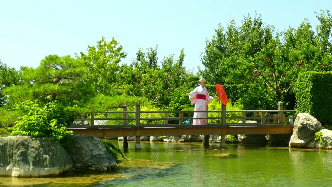 穿着和服的女人在公园的桥上走过池塘视频下载