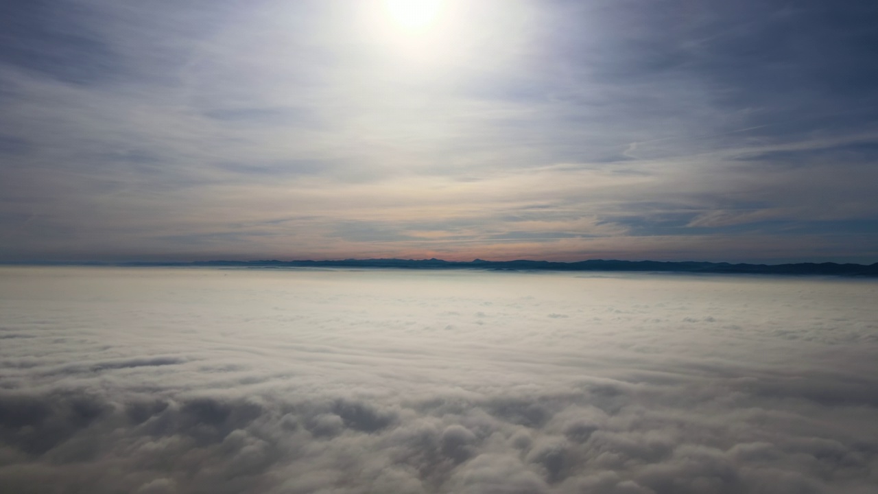 揭示从高空鸟瞰傍晚密集蓬松的积云飞行的镜头。从飞机窗口看到的令人惊叹的日落视频下载