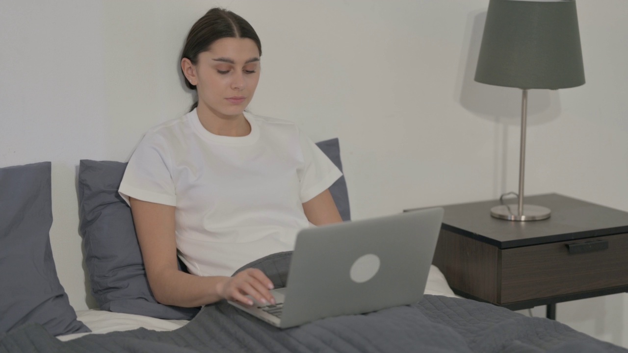 西班牙女性在床上用笔记本电脑工作视频素材