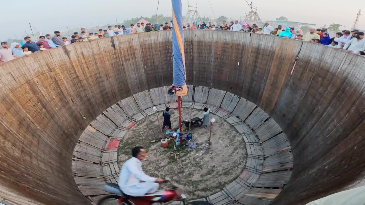 在农村地区的传统春节期间，一名特技摩托车手在表演结束后从死亡之井的顶部边缘向下移动。视频下载
