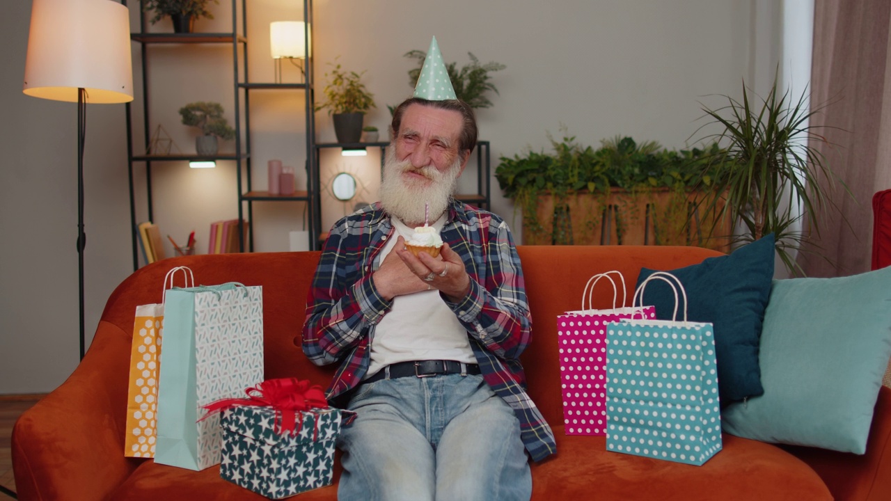 快乐老人们庆祝生日聚会，在小纸杯蛋糕上吹蜡烛许愿视频素材