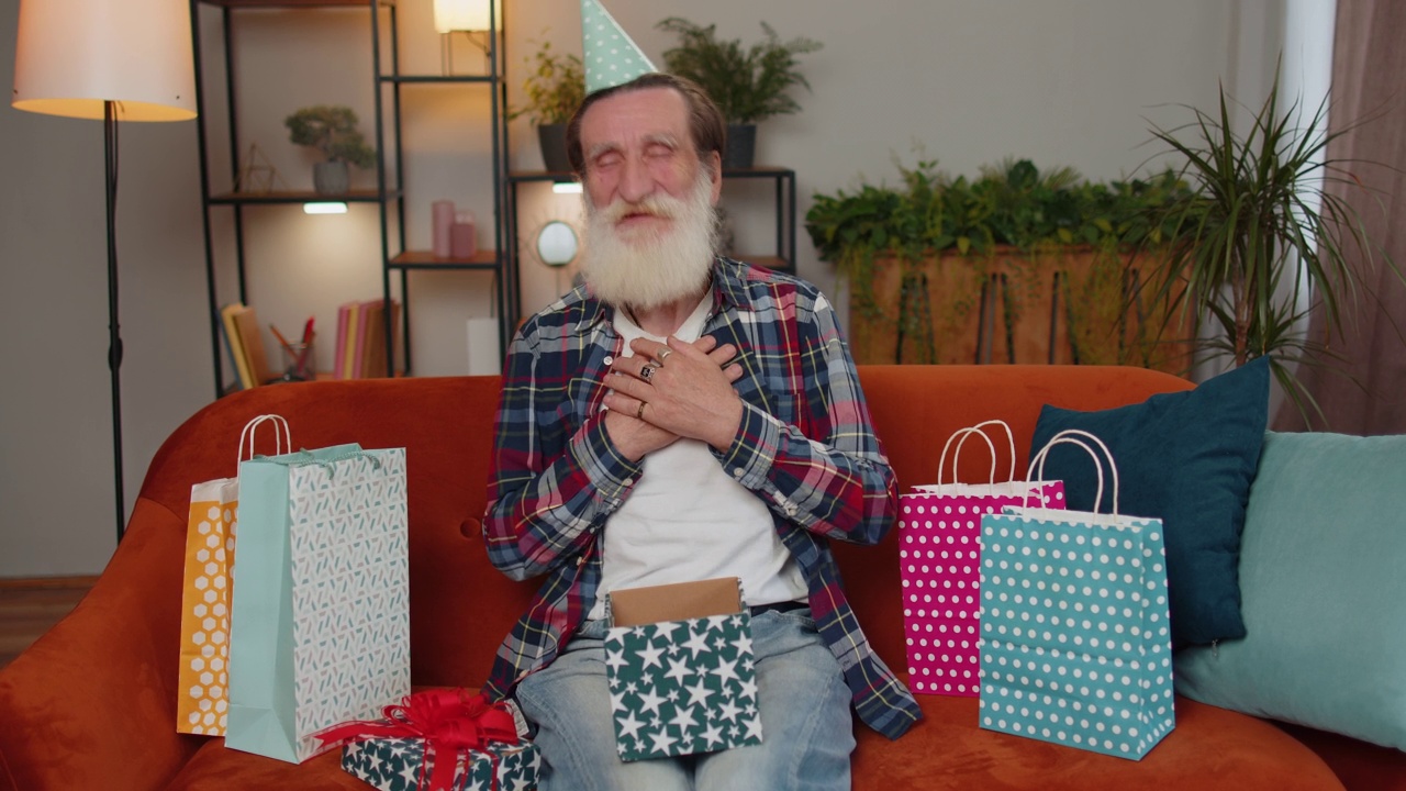 快乐的年长老人手持彩带生日礼盒，庆祝派对，打开家里的礼物视频素材