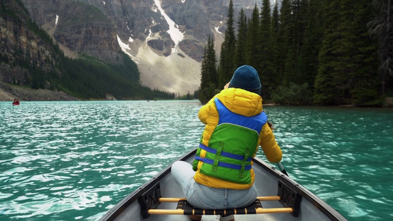 夏天在加拿大阿尔伯塔省班夫国家公园的冰碛湖上划独木舟的游客视频素材