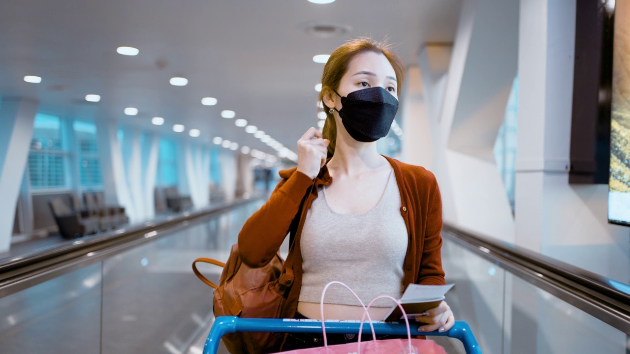 一位在机场自动扶梯上推着行李车的亚洲妇女视频素材
