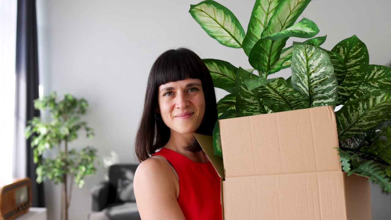 美丽的女人带着用纸箱包装的植物视频下载