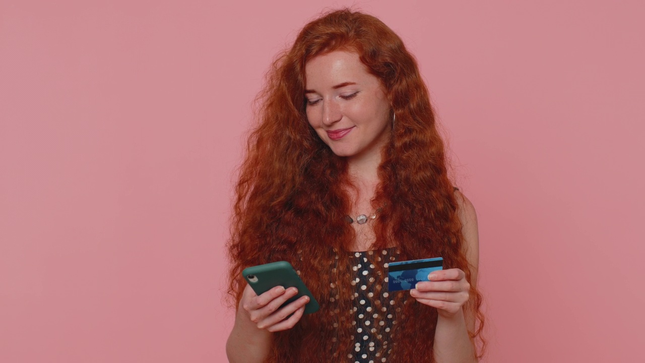 红发女孩在网上购物时使用信用卡和智能手机转账视频素材