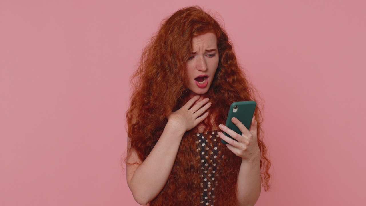 不开心的红发女人使用智能手机惊讶的彩票结果，坏运气，损失，不幸的消息视频素材