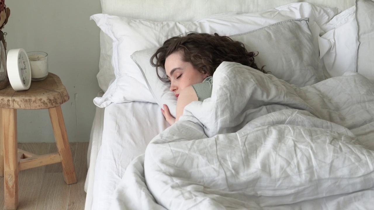 年轻漂亮的女人睡在舒适的床上视频素材