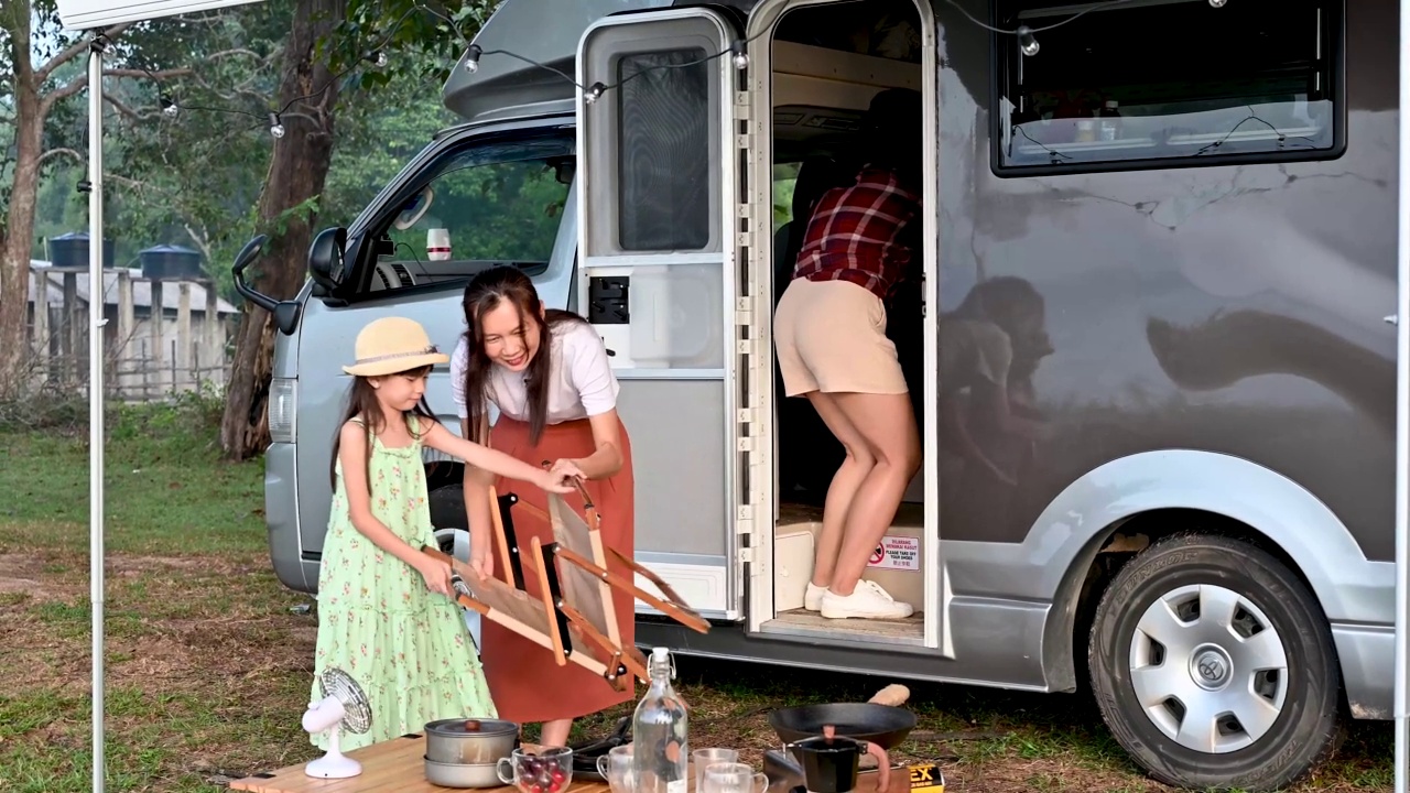 小亚洲女孩帮助她的母亲准备户外野餐期间露营车在海滩上视频素材
