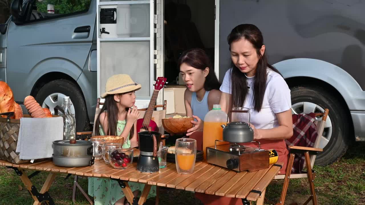 幸福的几代亚洲家庭享受食物和饮料在露营车的公路旅行在海滩上。露营车旅行系列视频素材