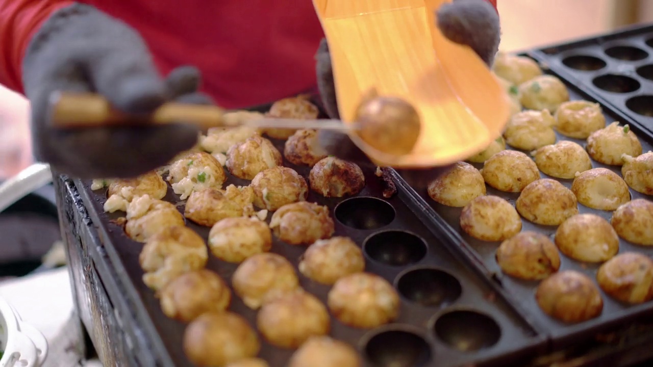 日本街头小吃，厨师将章鱼烧放在纸盘子里供顾客食用视频素材