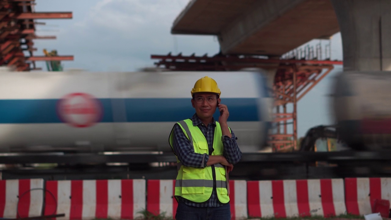 在建筑工地使用智能手机的工程师，在基础设施建筑工地戴安全帽的工头视频素材