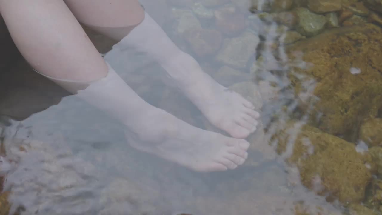 一位年轻女子的脚浸在河里视频素材