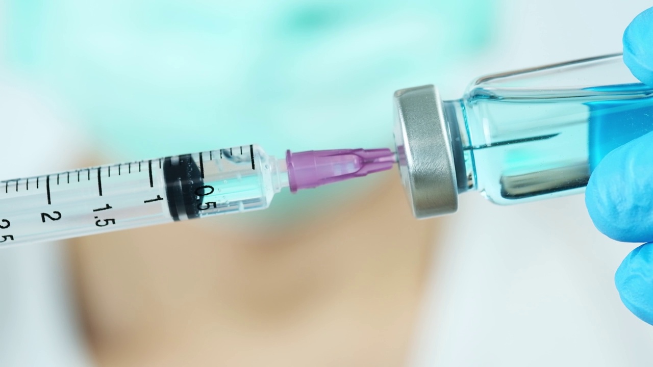 在医院里，医生的手拿着注射器和蓝色的疫苗瓶。健康和医学概念。视频素材