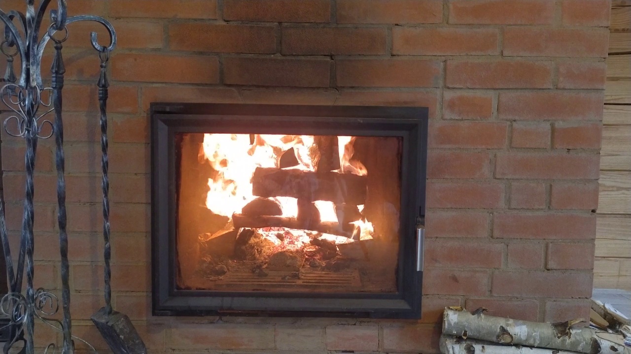 木头房子内部的壁炉里燃烧着熊熊的火焰。柴禾和一套壁炉设置在有火焰的炉膛附近。视频下载