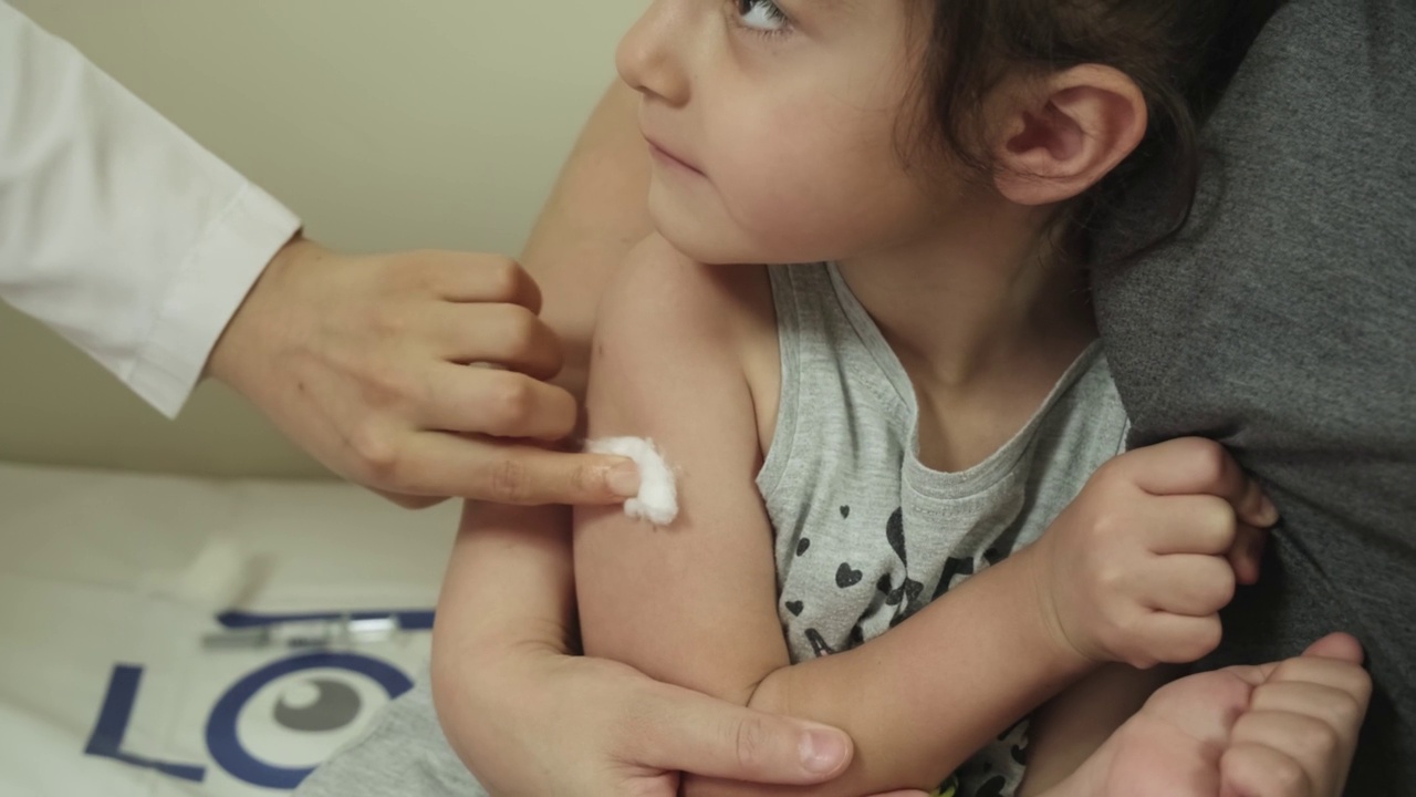 医生在诊所给孩子打针。大流行期间，小女孩从儿科医生那里接受流感注射。视频素材
