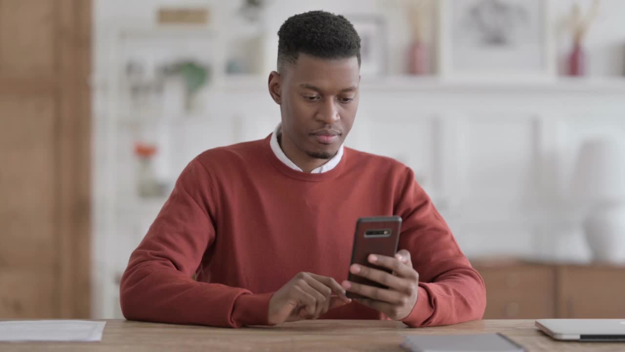 沮丧的非洲男子对智能手机上的损失做出反应视频素材