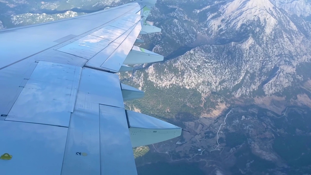 飞机在高山上空的蓝天上飞行。从飞机窗口看到的机翼。飞行和旅行的概念视频素材