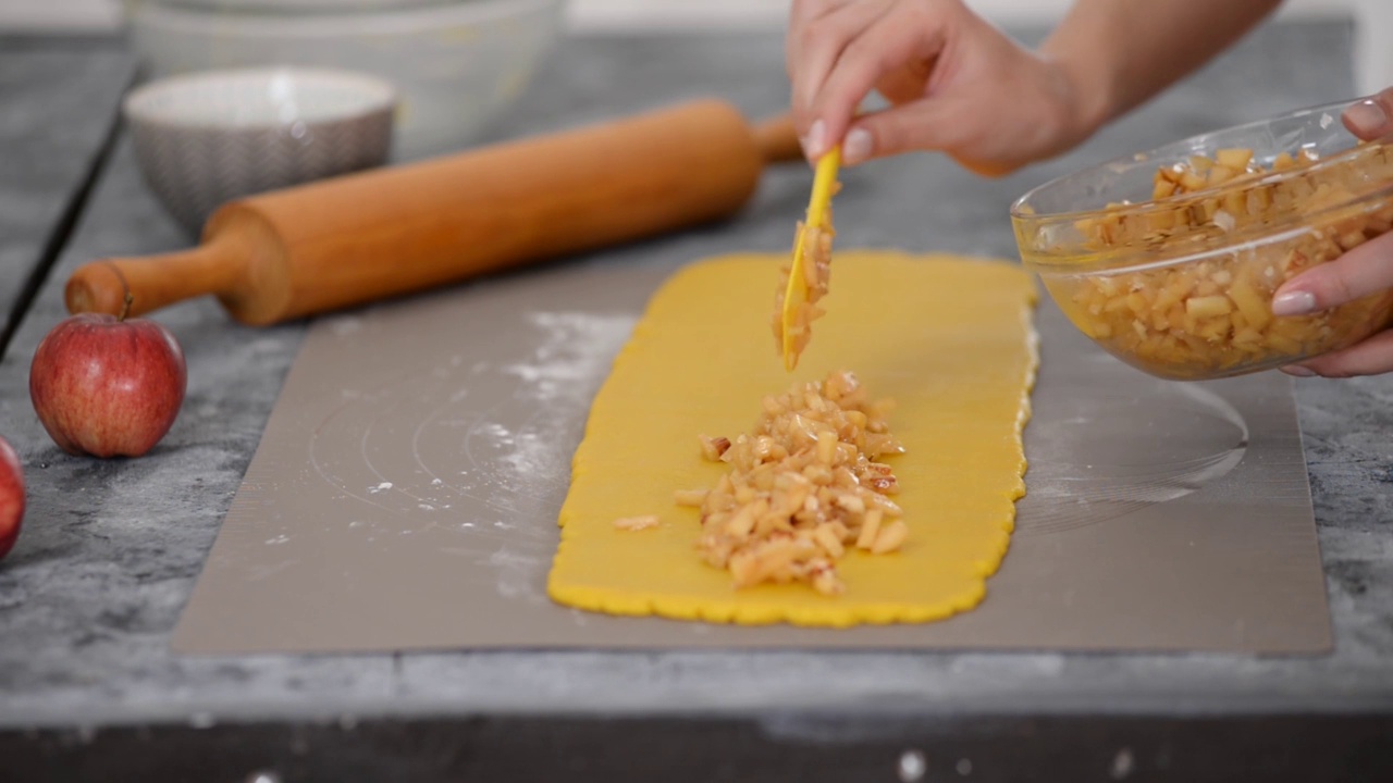 厨师把苹果片铺在薄薄的面团上。苹果派的制作过程。视频下载