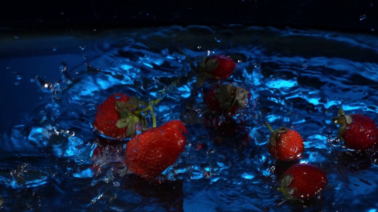 草莓落入水中的慢镜头。用高速摄像机拍摄，4k画面视频下载